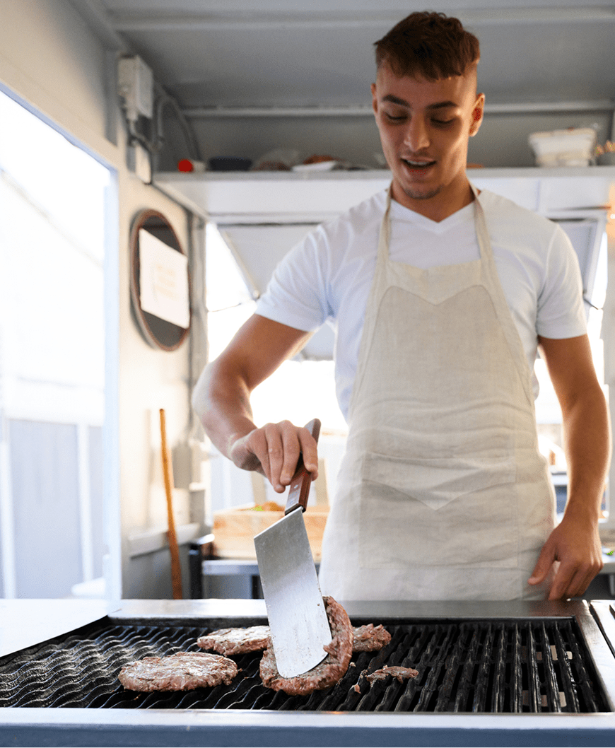 Person flipping patties on barbecue